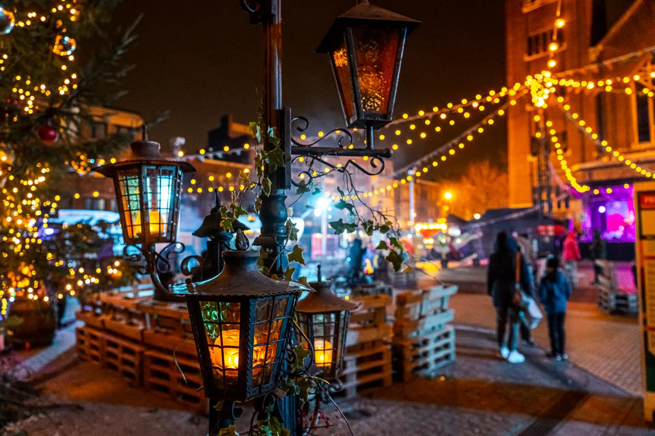 Sfeerfoto van een kerstmarkt met tenten, ambachten en lichtjes