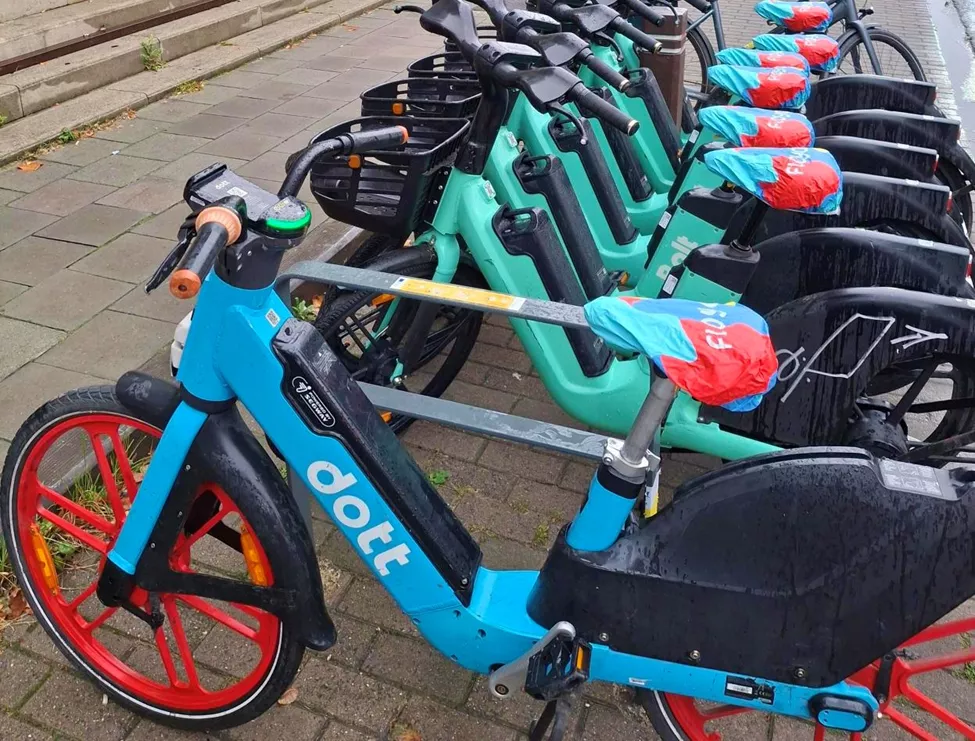 Zone de stationnement contenant des vélos Dott et Bolt, avec une housse de selle Floya