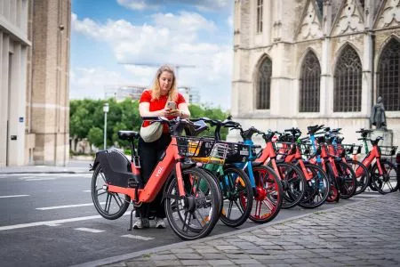Persoon die een Voi-fiets ontgrendelt in een dropzone waar ook Bolt en Dott te zien zijn